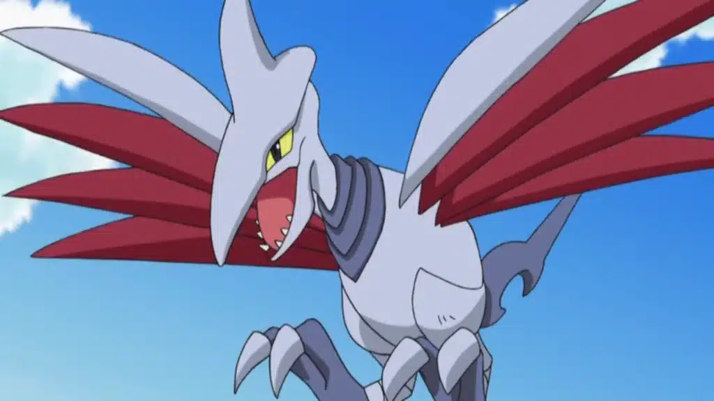 Skarmory flying with metal wings spread wide, showing its sharp beak and armored body against a clear blue sky